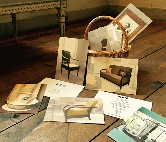 Lattialla kuvia huonekaluista. Kuvien takana punottu kori, josta pilkottaa lisää kuvakortteja.