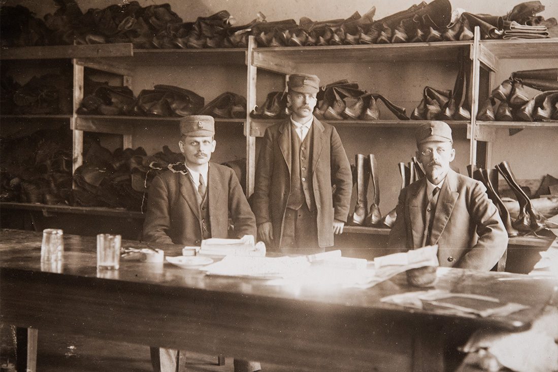 1618_118_netti Todennäköisesti suojeluskuntalaisia, suutarimestari A. Koponen ja useita kippurakärkisiä lapikkaita. Suojeluskuntalaiset käyttivät jalkineina saappaita tai lapikkaita. Kuva: KUHMU