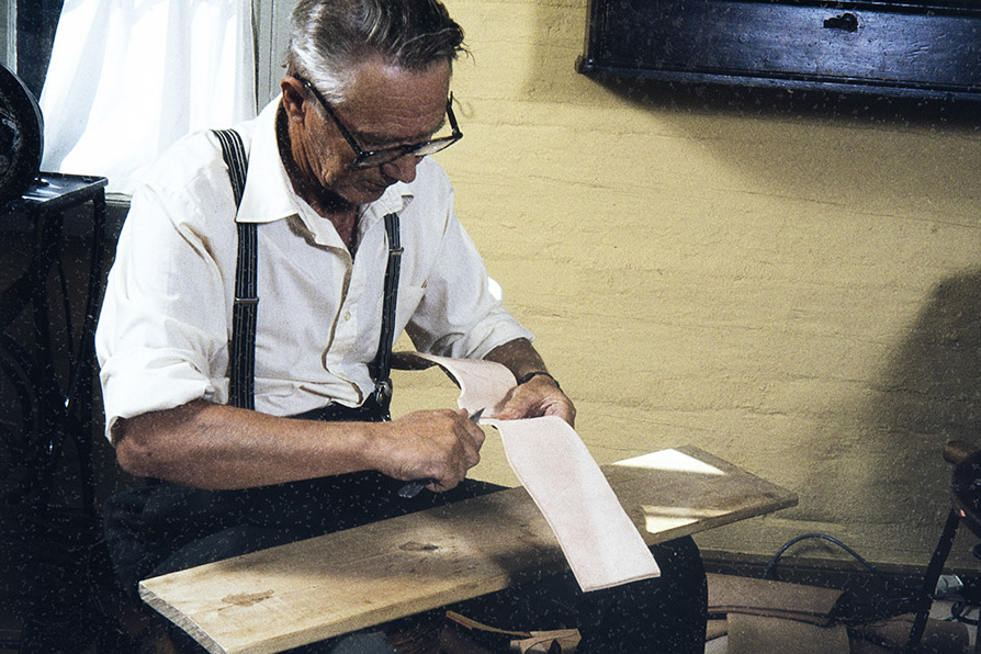 5a_2282_035_netti Suutari Vihtori Heikkinen leikkaa äären eli kengän sivujen nokasta nurkan v. 1982. Kuva: Kari Jämsén / KUHMU