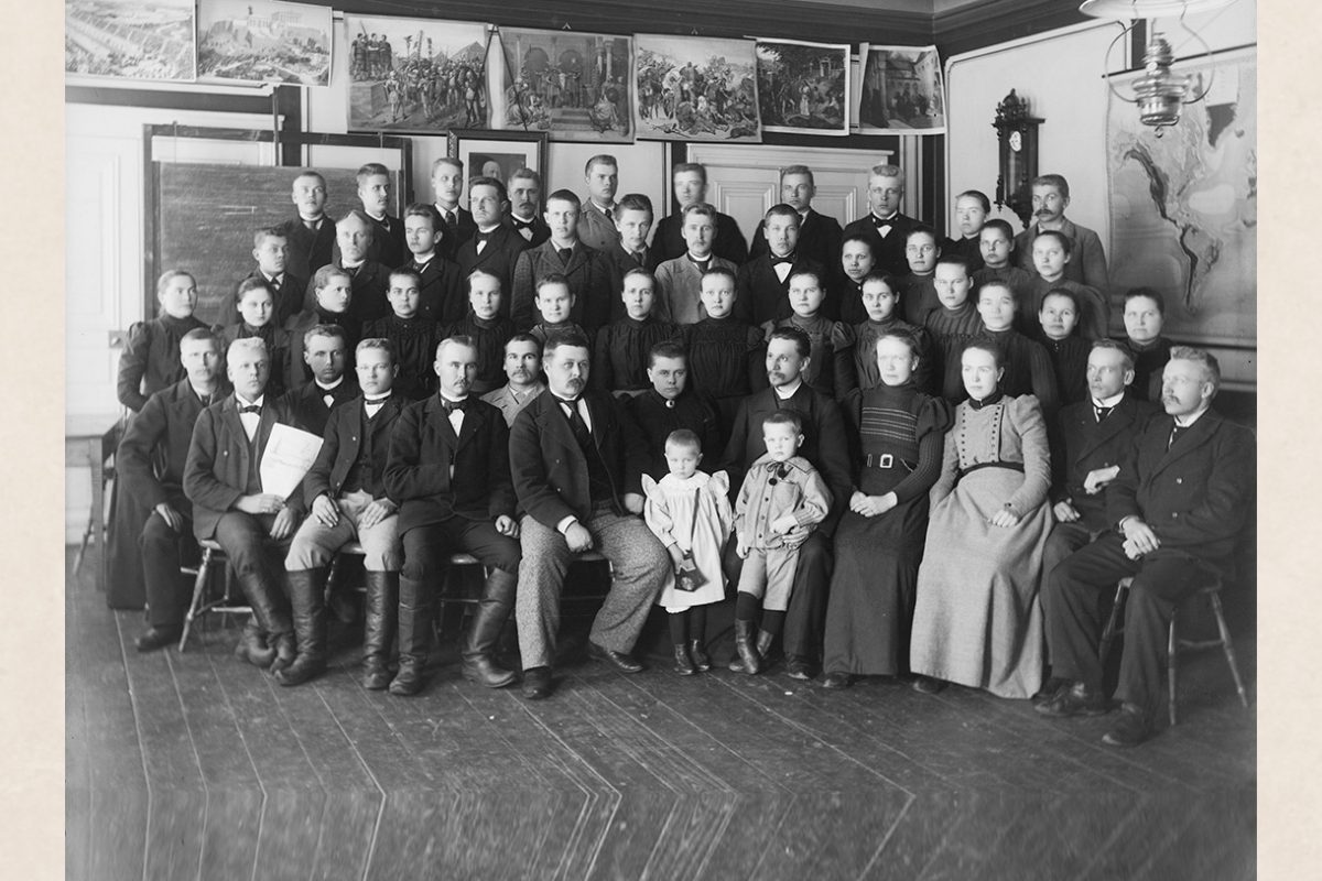 B1004_netti Group photo of North-Savo Folk High School students in Halola, Maaninka, 1896-1899. In the front row, seated on the left are wearing Finnish boots, the children in the front, button boots. In the photo, 1st row (from left): 5. Tellervo Mikander in front of Augusta Mikander 6. Aarne Mikander in front of Hjalmar Mikander. Photo: Victor Barsokevitsch / KUHMU