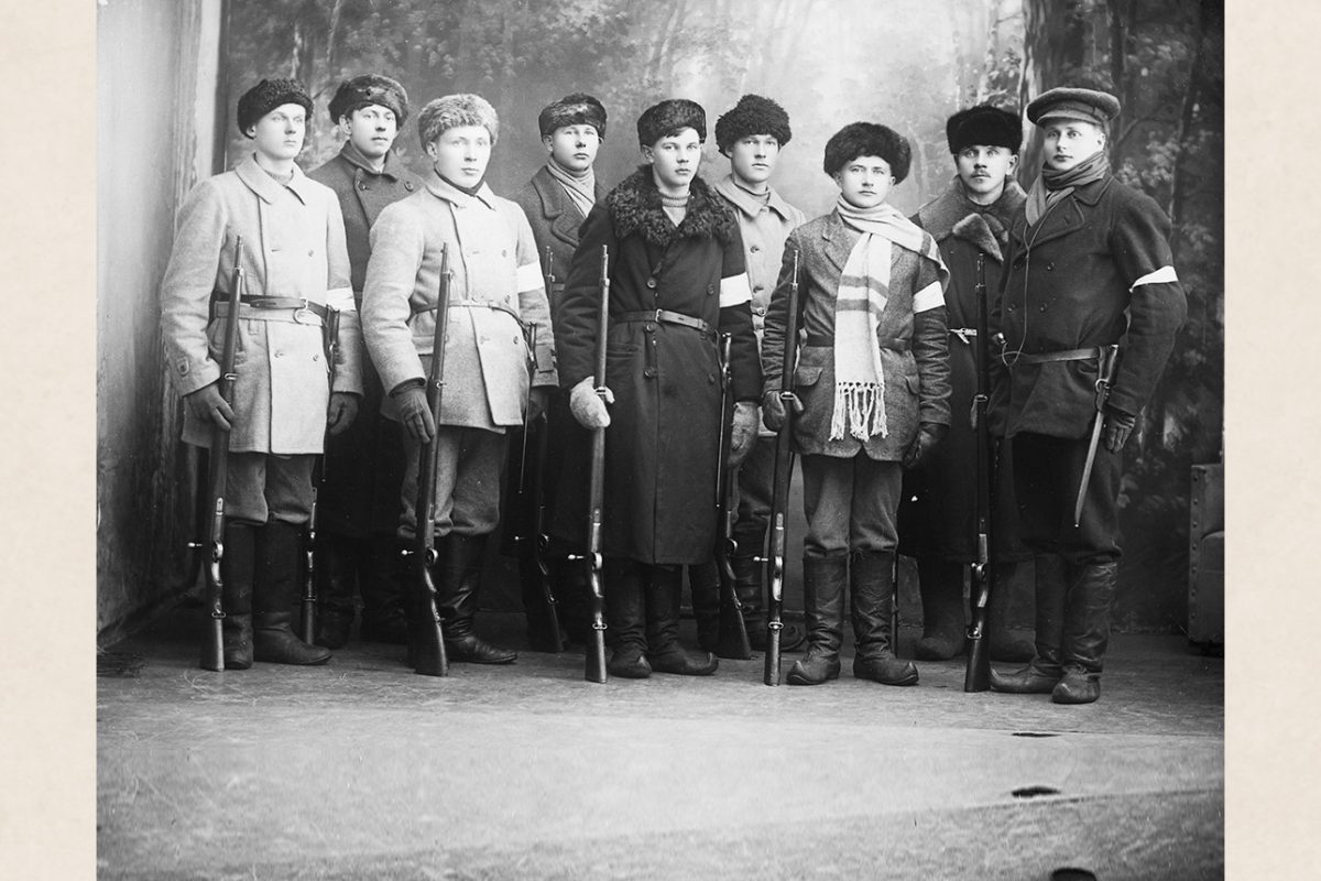 B247_netti Nilsiän suojeluskuntalaisia v. 1918 Victor Barsokevitschin ateljeessa kuvattavana. Usealla suojeluskuntalaisena on kuvassa jalkineena kippurakärkiset lapikkaat. Kuvassa oikealta Atte Pirinen, Verneri Lappalainen, Eino Pentikäinen, Jalmari Niemi, Emil Kokkonen, Pekka Pietikäinen, Hannes Pietikäinen, Juha Taskinen, Antti Taskinen. Kuva: Victor Barsokevitsch / KUHMU