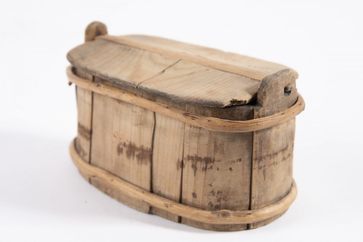 Vaaleaa puuta oleva pieni kannellinen puuastia.