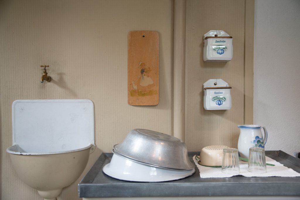 Astioiden pesussa käytettävät vadit tiskipöydän päällä sekä seinässä oleva vesihana ja sen alapuolella oleva erillinen kaatoallas.