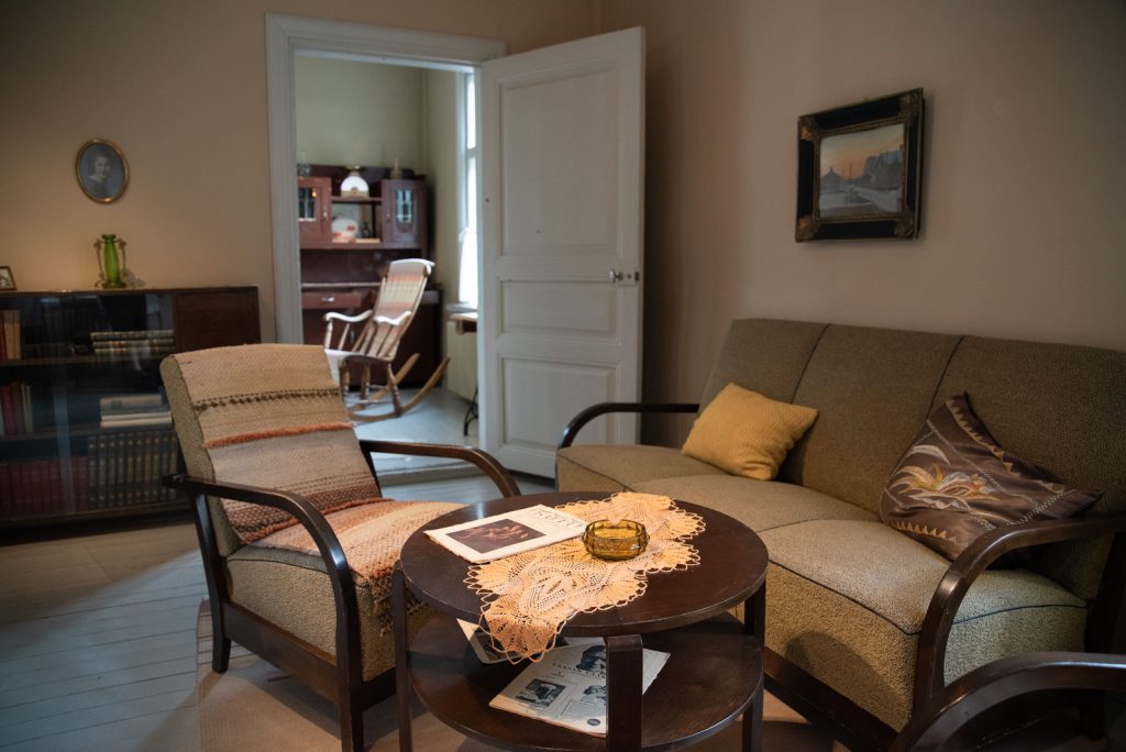 Sohva, nojatuoli ja sohvapöytä, jonka päällä on aikakauslehtiä.