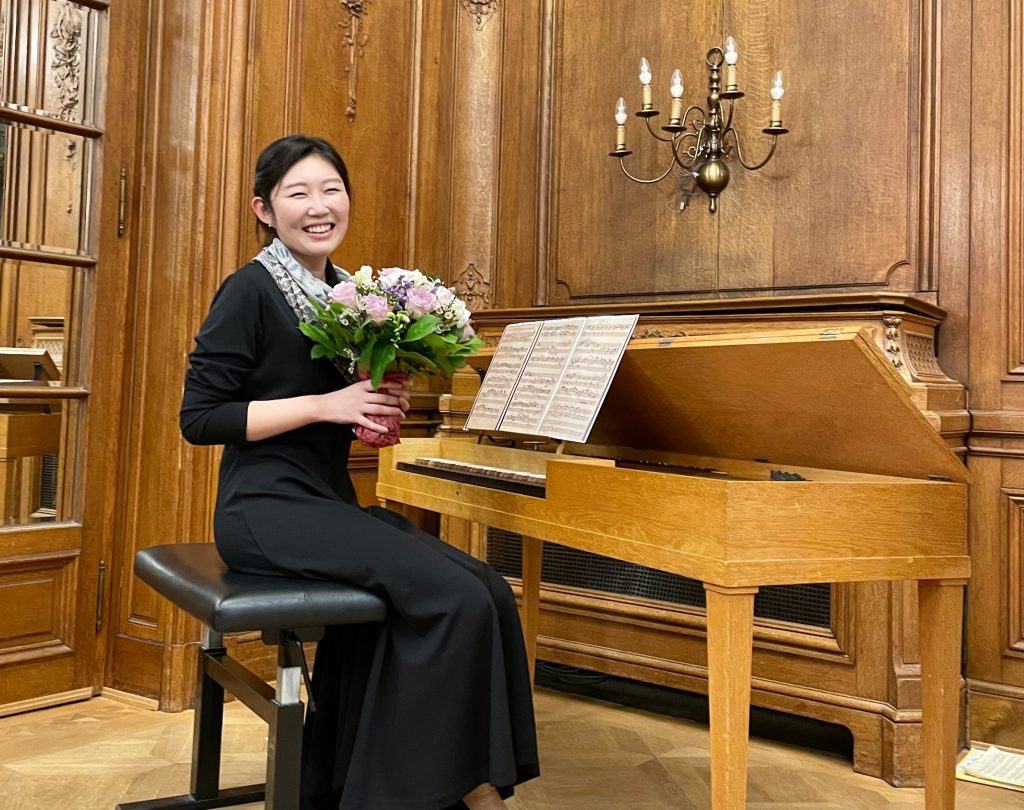 Muusikko istuu pianon edessä kukkakimppu käsissään.